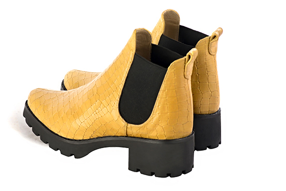 Mustard yellow and matt black women's ankle boots, with elastics. Round toe. Low rubber soles. Rear view - Florence KOOIJMAN